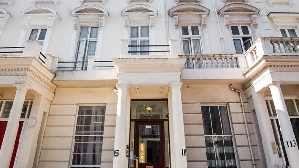 Un edificio blanco con múltiples ventanas y una entrada central con columnas.