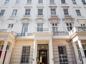 Un bâtiment blanc doté de nombreuses fenêtres et d’une entrée centrale ornée de colonnes.