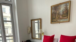 Habitación de hotel con una cama grande, un escritorio, una silla, una lámpara y un cuadro en la pared.