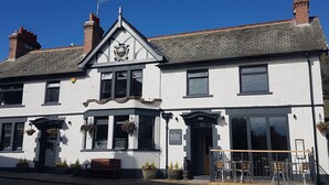 A white building with a black awning, a sign reading "The Bowes Hotel," and a wooden bench outside. - The Bowes Hotel (Hexham)