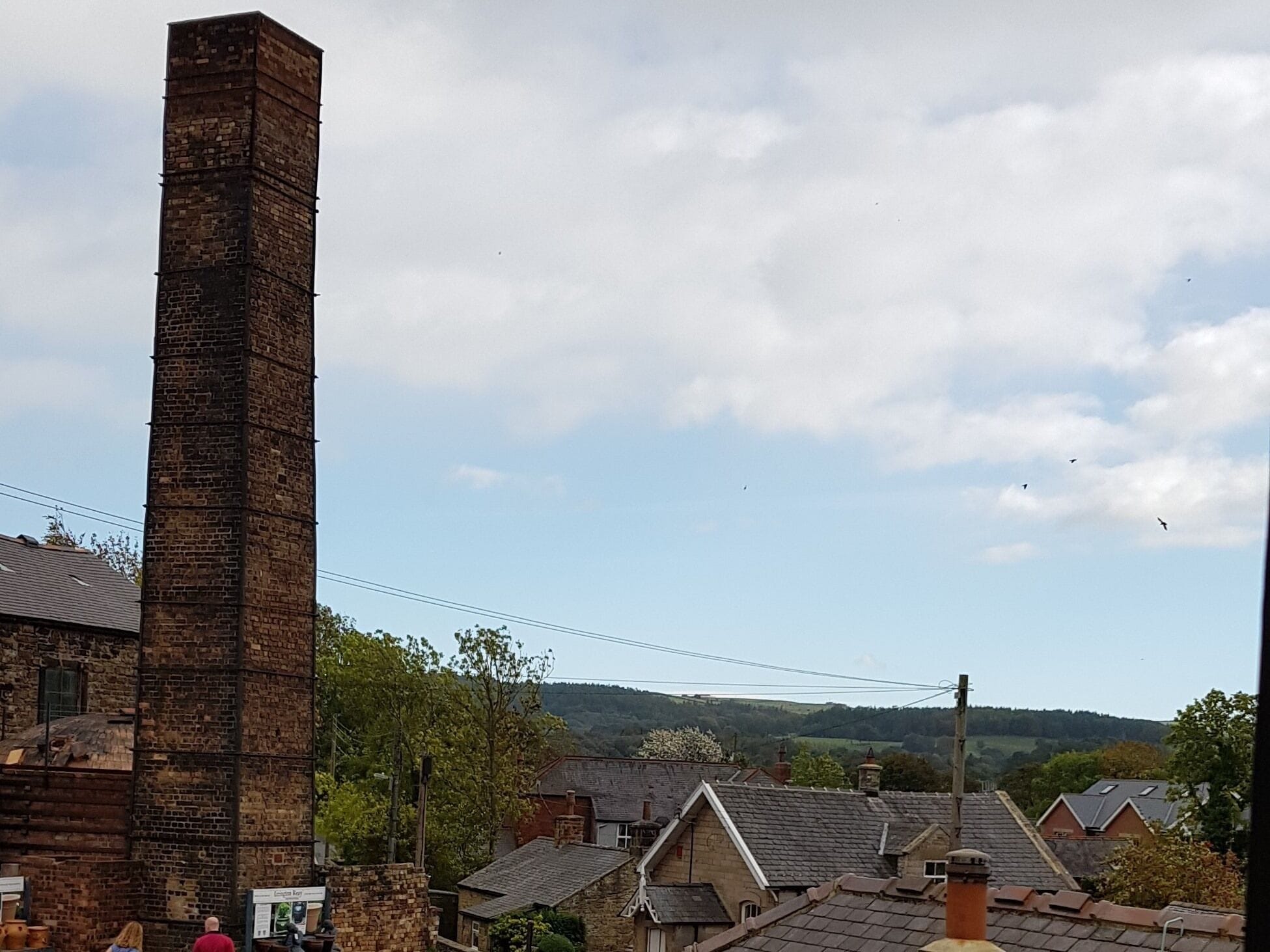 Una chimenea de ladrillo, casas tradicionales y un paisaje montañoso.