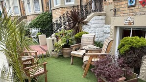 A courtyard with a small lawn, wooden furniture, and potted plants. - Albemarle Hotel (Scarborough)