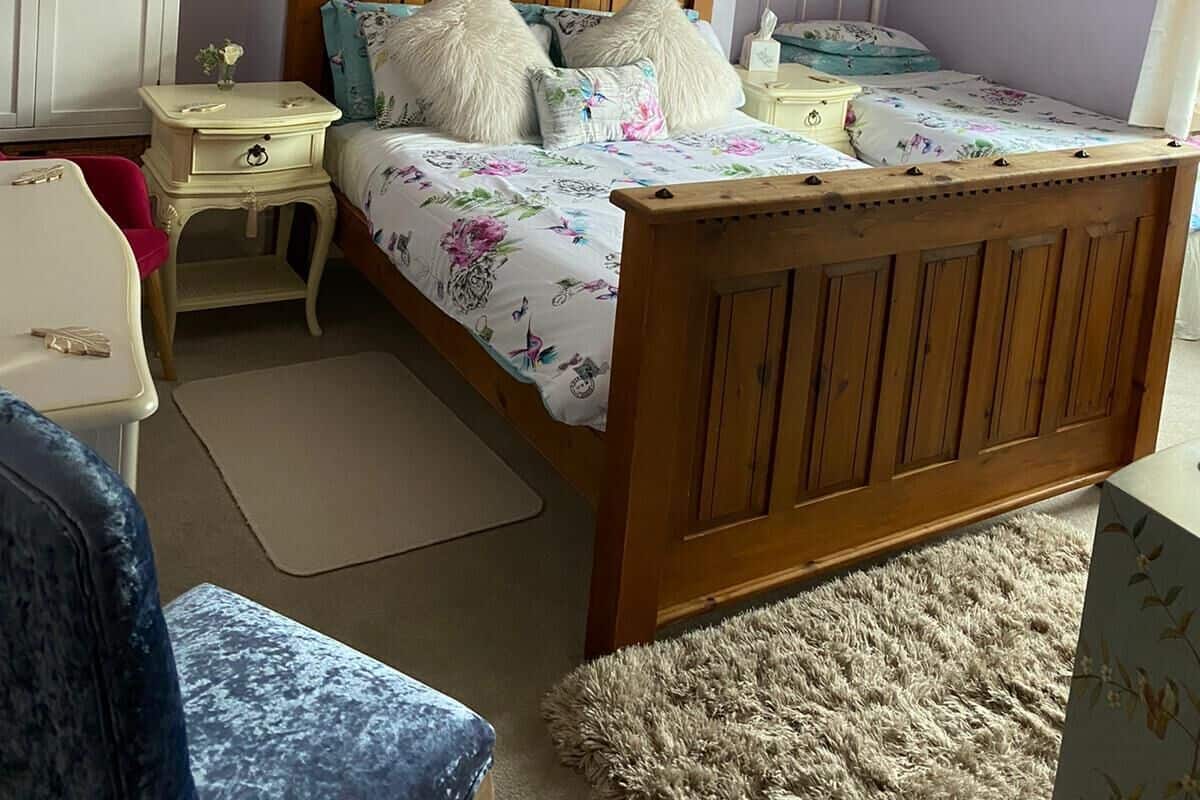 Ein Schlafzimmer mit einem Holzbett, einem Nachttisch, einer Kommode und einem Spiegel an der Wand.