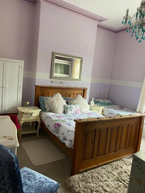 A bedroom with a wooden bed, a nightstand, a dresser, and a mirror on the wall. - Albemarle Hotel (Scarborough)