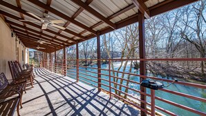 A covered outdoor area with benches, a railing overlooking a river, and a view of trees and buildings in the background. - River Bend Inn (Pigeon Forge)