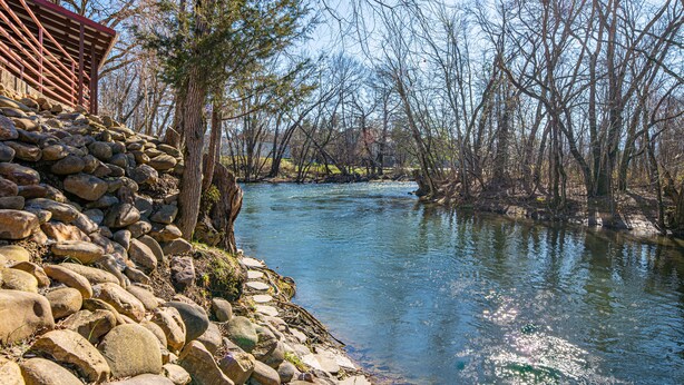 A stone wall with a wooden structure beside a river. - River Bend Inn (Pigeon Forge)