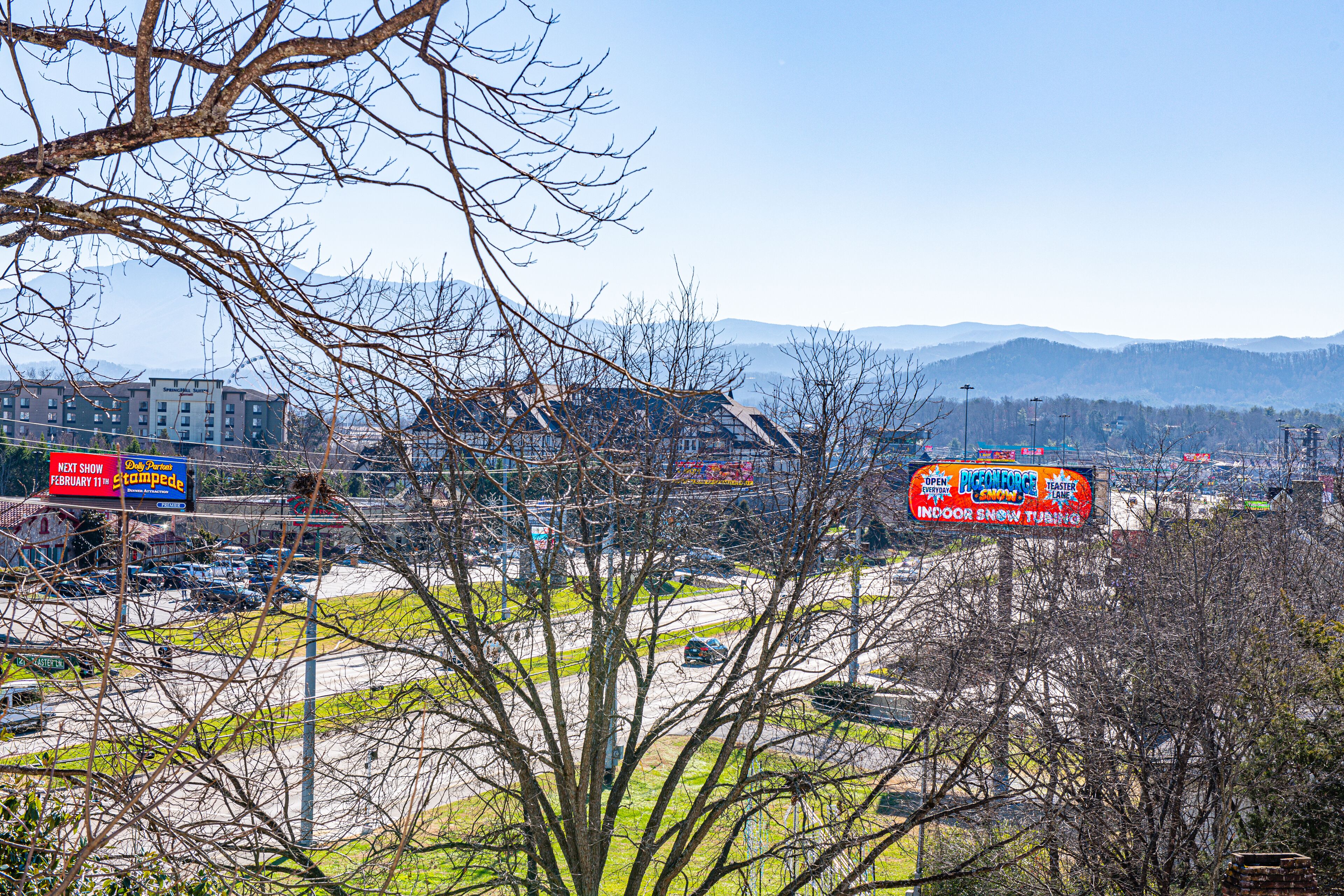 A parking lot with cars, a building, and a signboard.