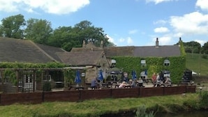 A riverside pub with outdoor seating and a stone wall. - The Old Mill Knitsley (Consett)