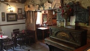 A rustic room with a piano, wooden furniture, and a clock on the wall. - The Old Mill Knitsley (Consett)