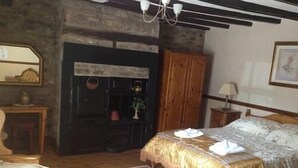 A bedroom with a bed, wooden furniture, a stone fireplace, and a mirror. - The Old Mill Knitsley (Consett)