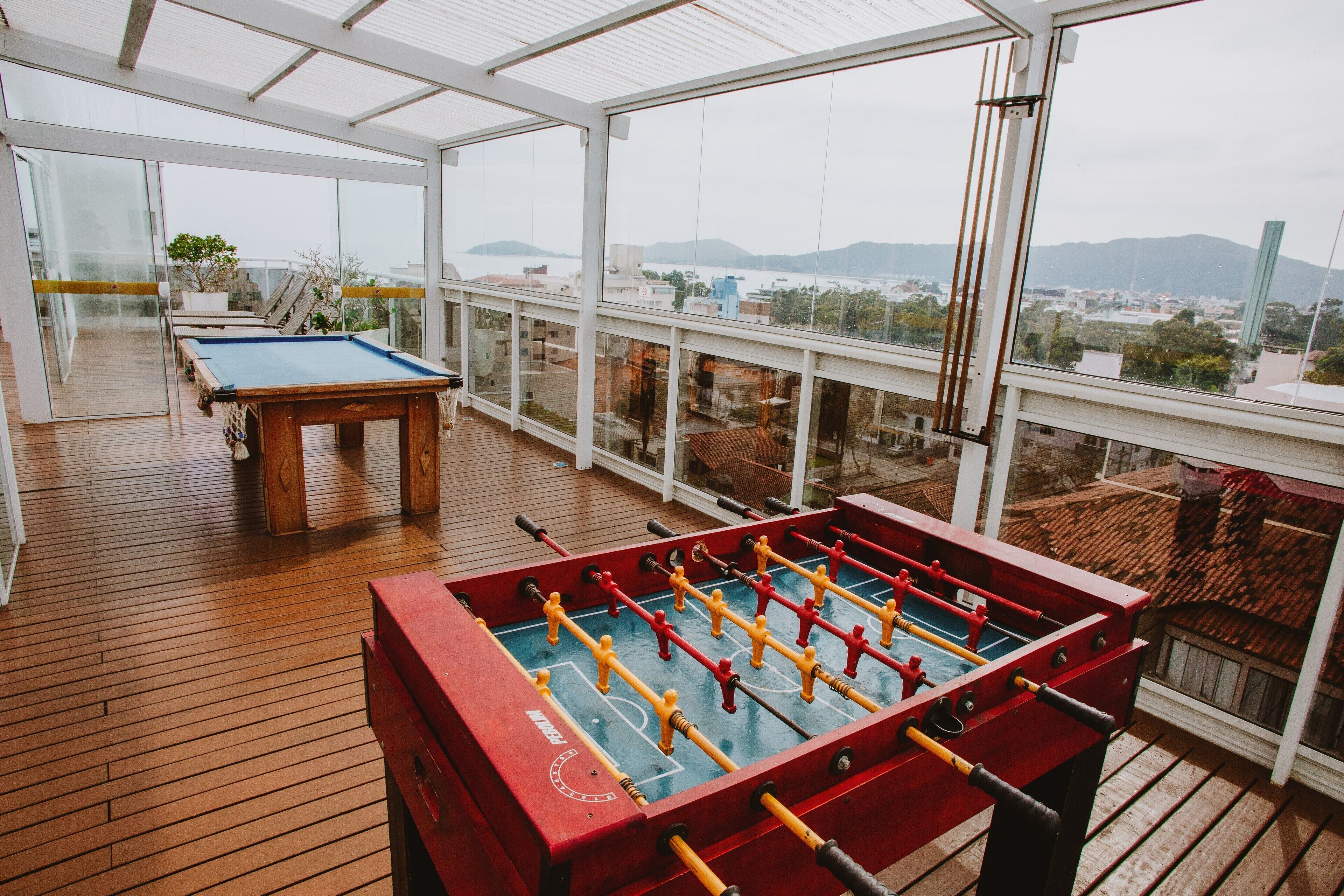 A spacious indoor area with a foosball table, a pool table, and a view of a cityscape through large windows.