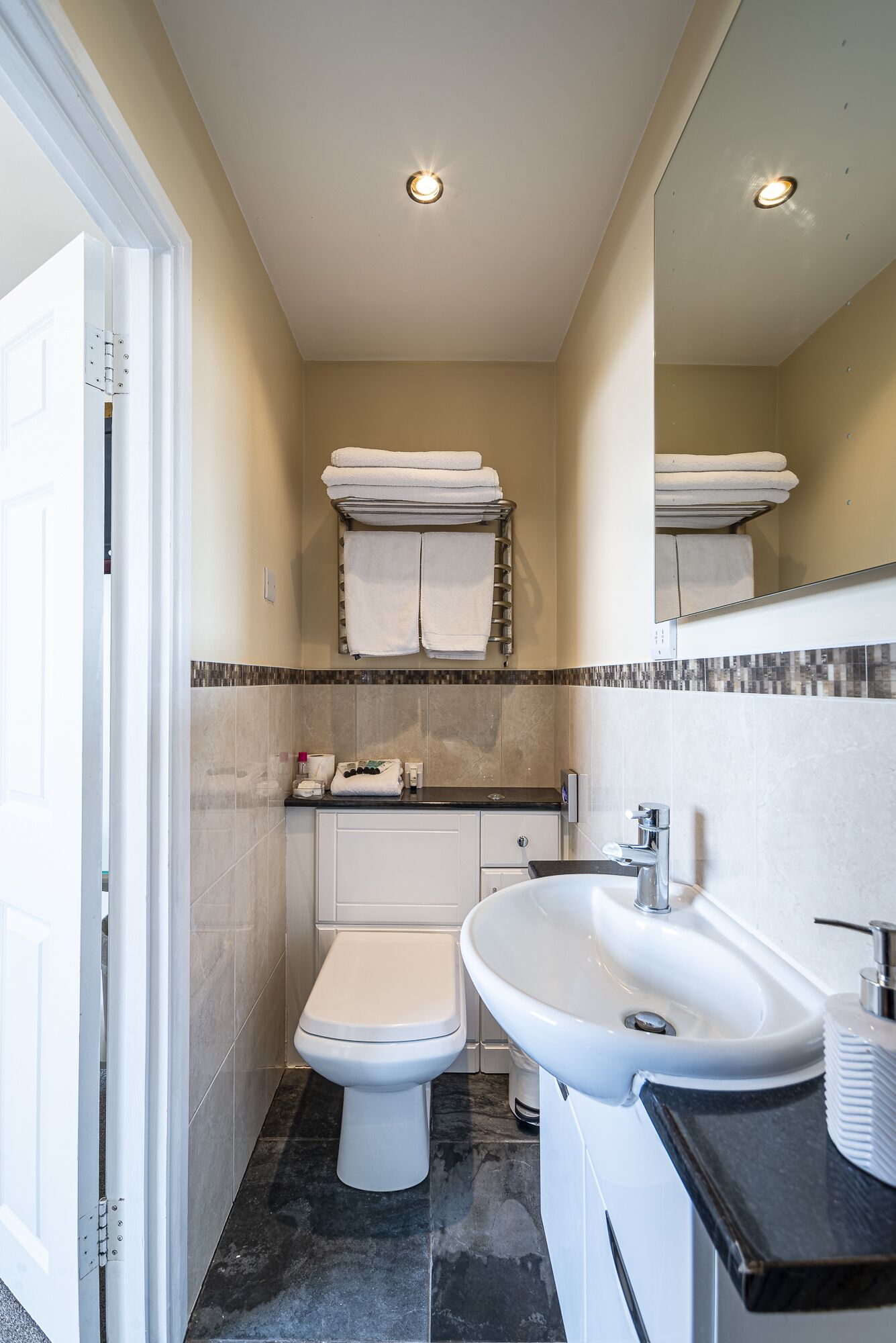 Een moderne badkamer met toilet, wastafel en handdoekhouder.