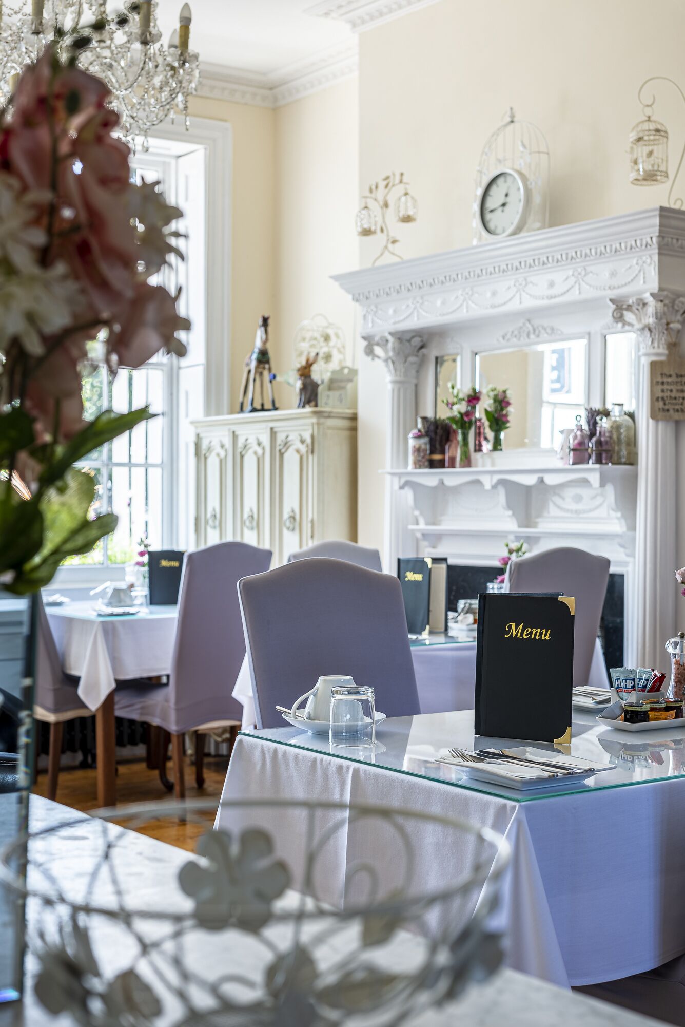 Un espace repas avec des tables dressées, un présentoir à menus et une cheminée décorative.