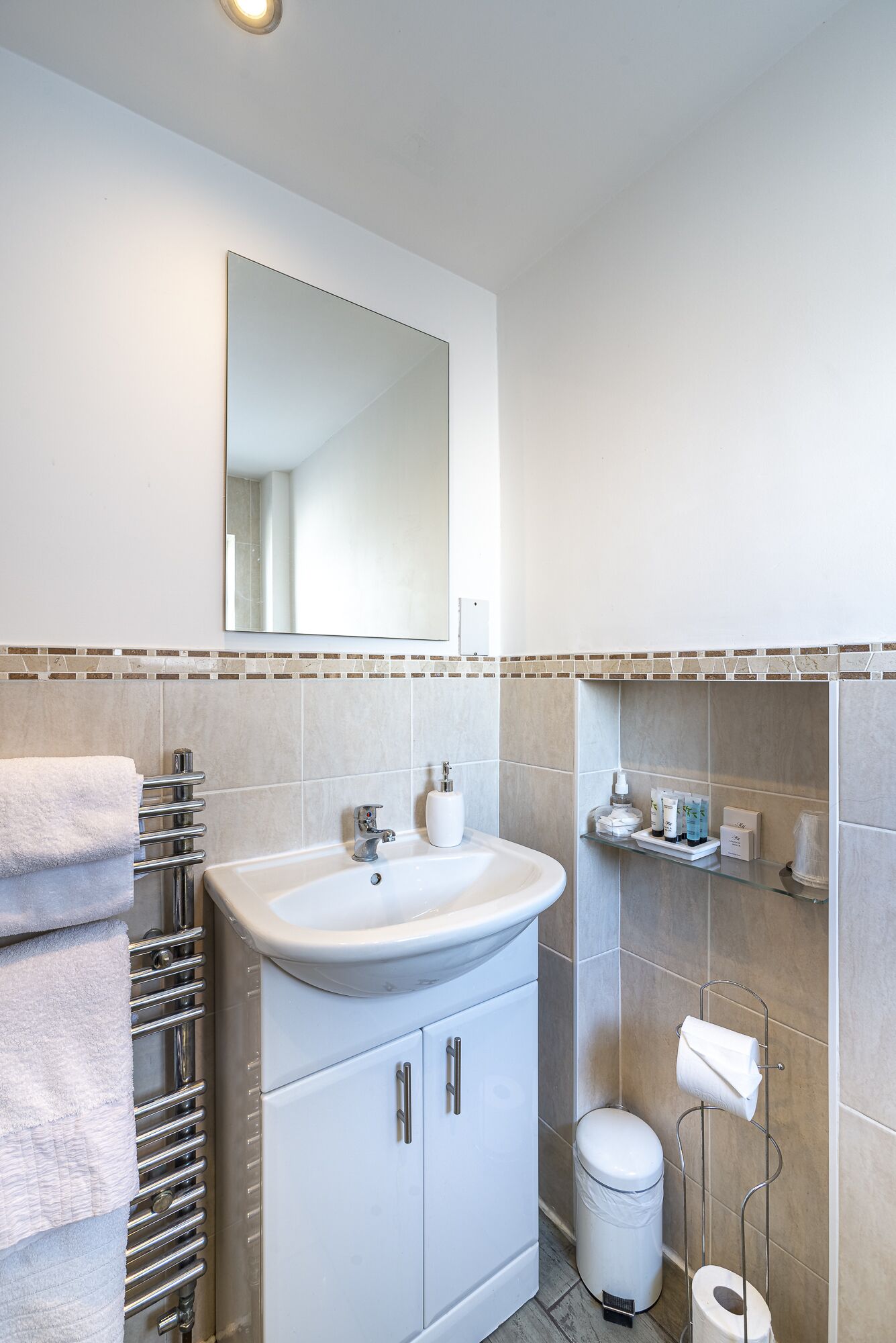 Une salle de bain moderne avec un lavabo blanc, un porte-serviettes chromé et un miroir au-dessus du lavabo.