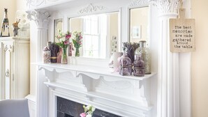 A white fireplace mantel with decorative items, a mirror, and a sign with a quote.