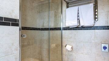 Une salle de bain avec une douche à parois de verre, des toilettes et un porte-serviettes avec des serviettes pliées.