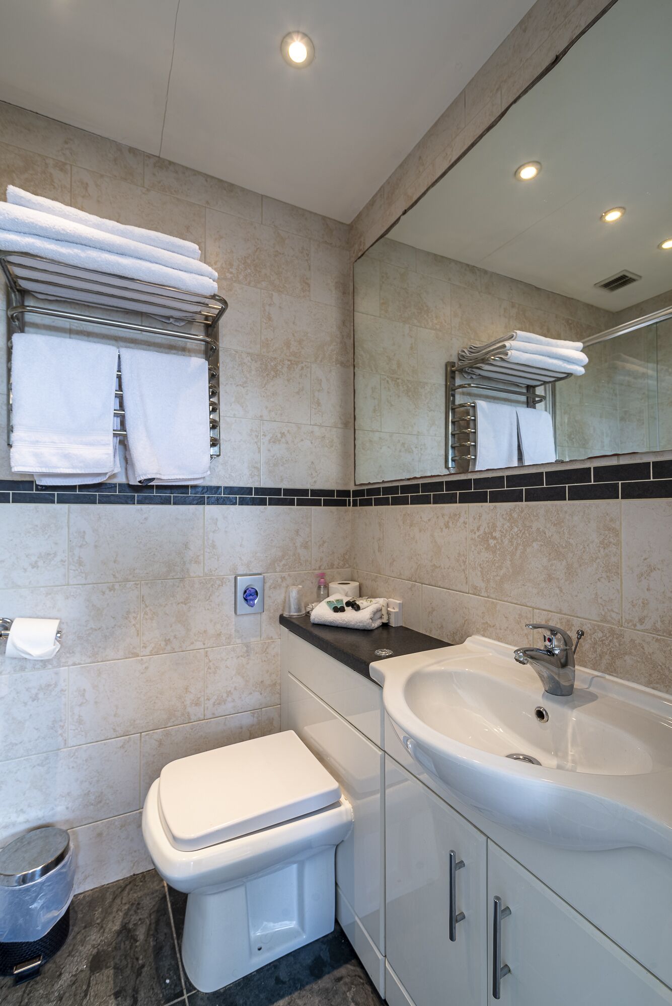 A modern bathroom with a toilet, sink, and towel rack.