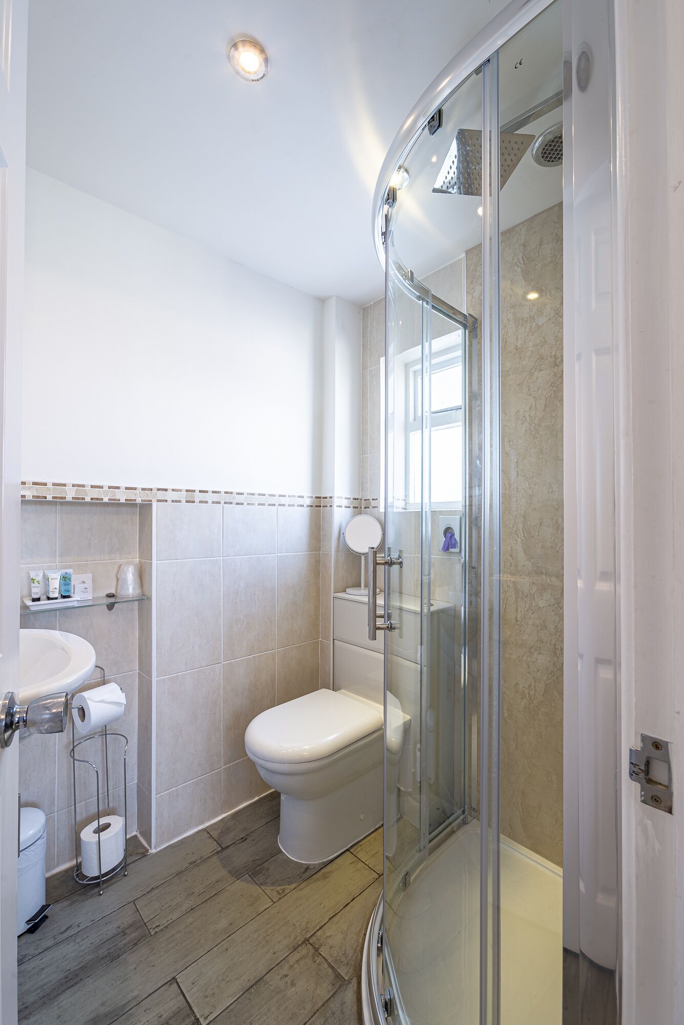 A modern bathroom with a glass shower enclosure, a toilet, and a sink with a towel rack.