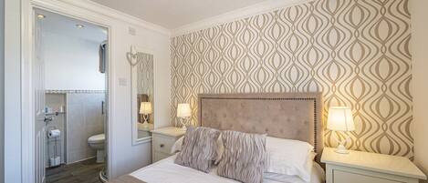 A bedroom with a bed, bedside tables, a mirror, and a patterned wall.