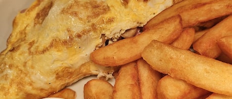 A plate with a fried egg, fries, and peas.