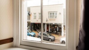 Een raam met uitzicht op een straatbeeld, inclusief geparkeerde auto's en gebouwen.