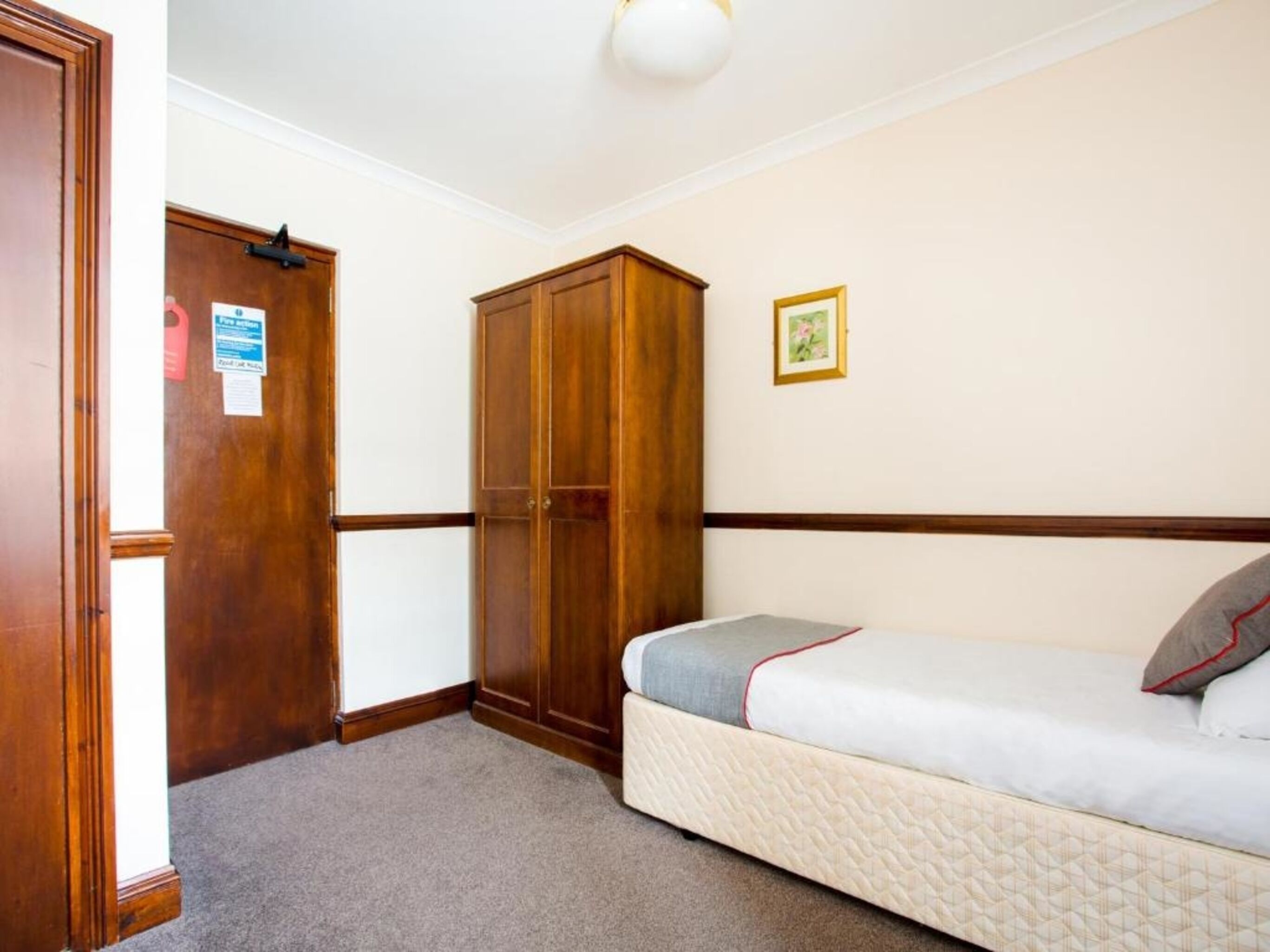 A bedroom with a bed, a wardrobe, and a door.