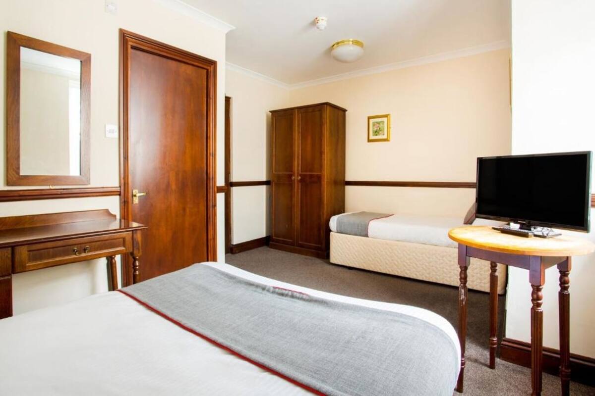 A hotel room with a bed, a television, a wardrobe, and a desk.