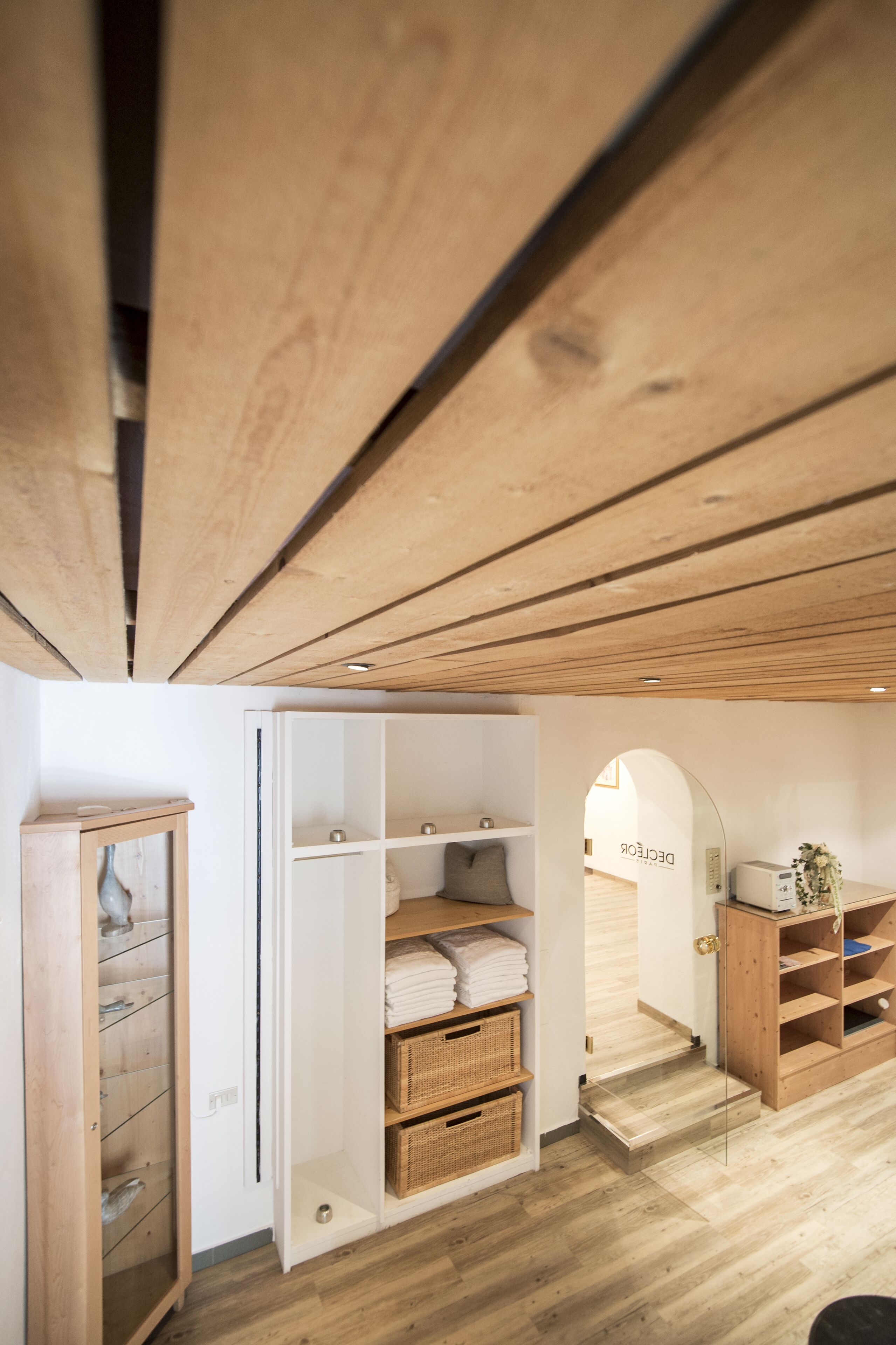 Eine Holzbalkendecke mit eingebautem Kleiderschrank und Regalen, eine weiße Tür und eine kleine Treppe zu einem anderen Raum.