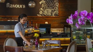 Een restaurantinterieur met een houten toonbank, een menubord en een vitrine met etenswaren.