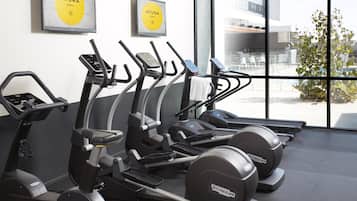 Un gimnasio con cintas de correr, una máquina de remo y una bicicleta estática.