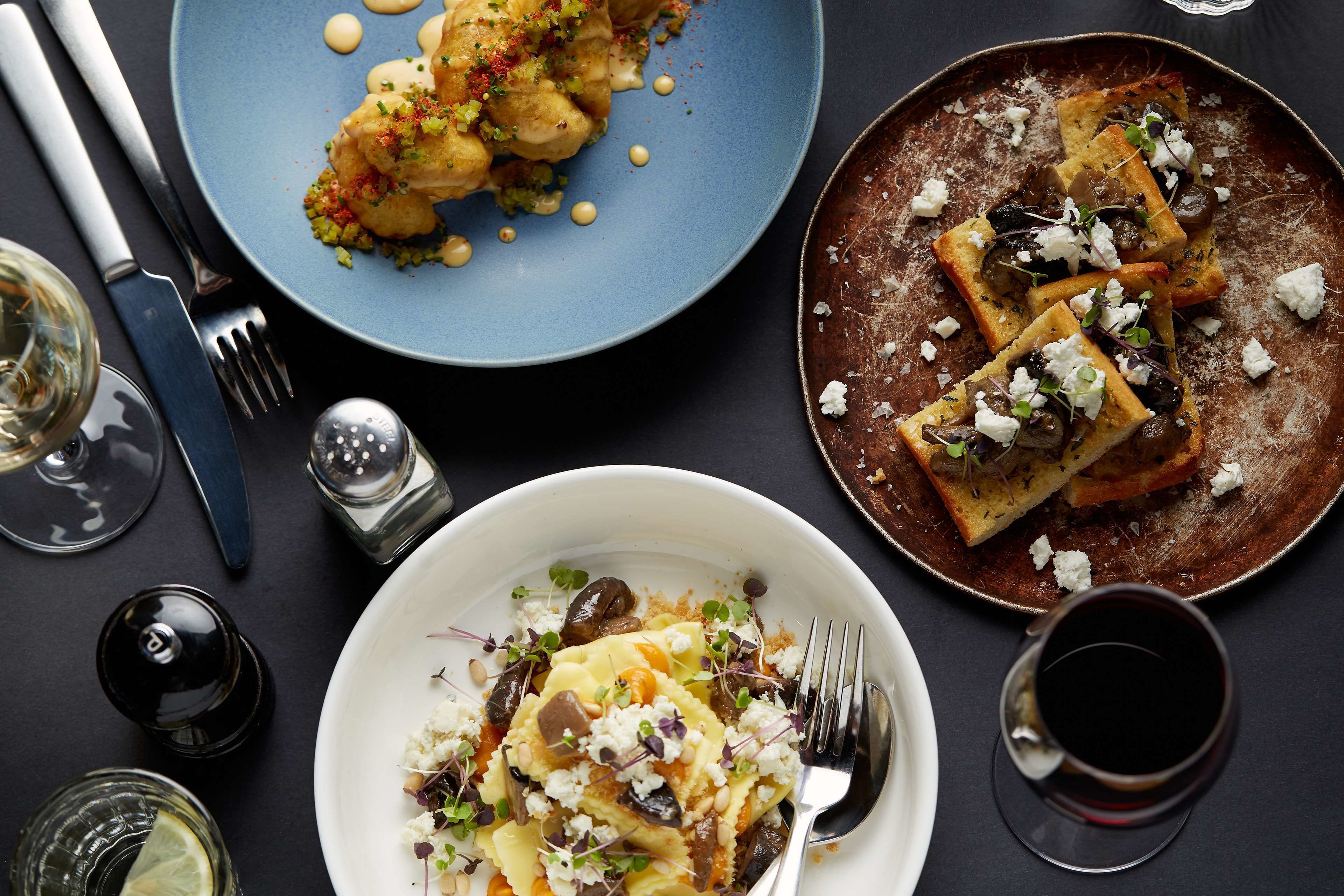 A dining table with plates of food, cutlery, and glasses.