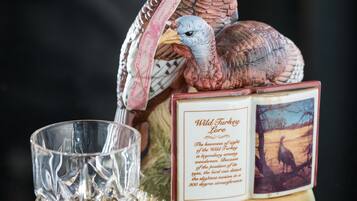 Ein Stapel Bücher mit dem Titel 'Wild Turkey' und ein Glas Whiskey daneben.