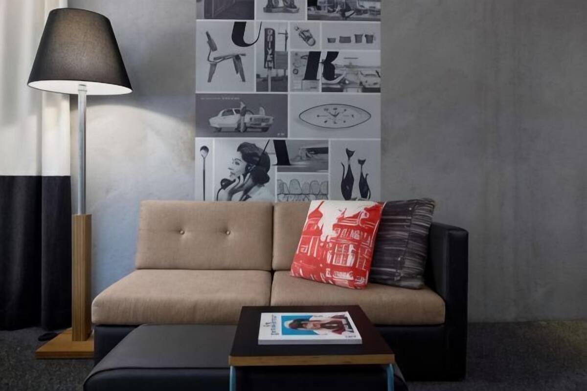 A modern living room with a sofa, a coffee table, a floor lamp, and a wall with black and white photographs.