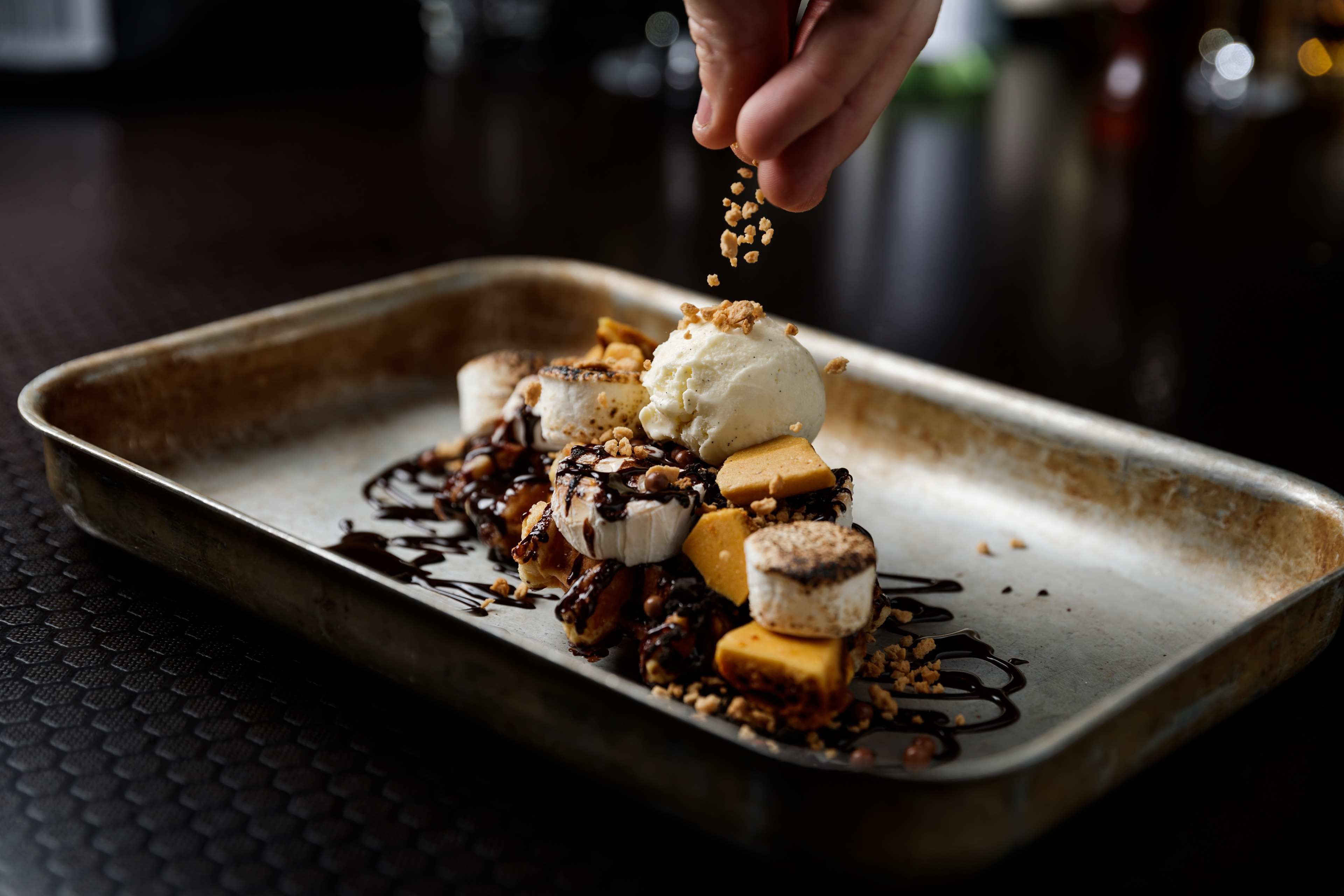 A dessert tray with ice cream, bananas, and chocolate sauce.