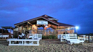 A beachside restaurant with outdoor seating and a covered patio area. - Bojo Beach Resort (Bortianor)