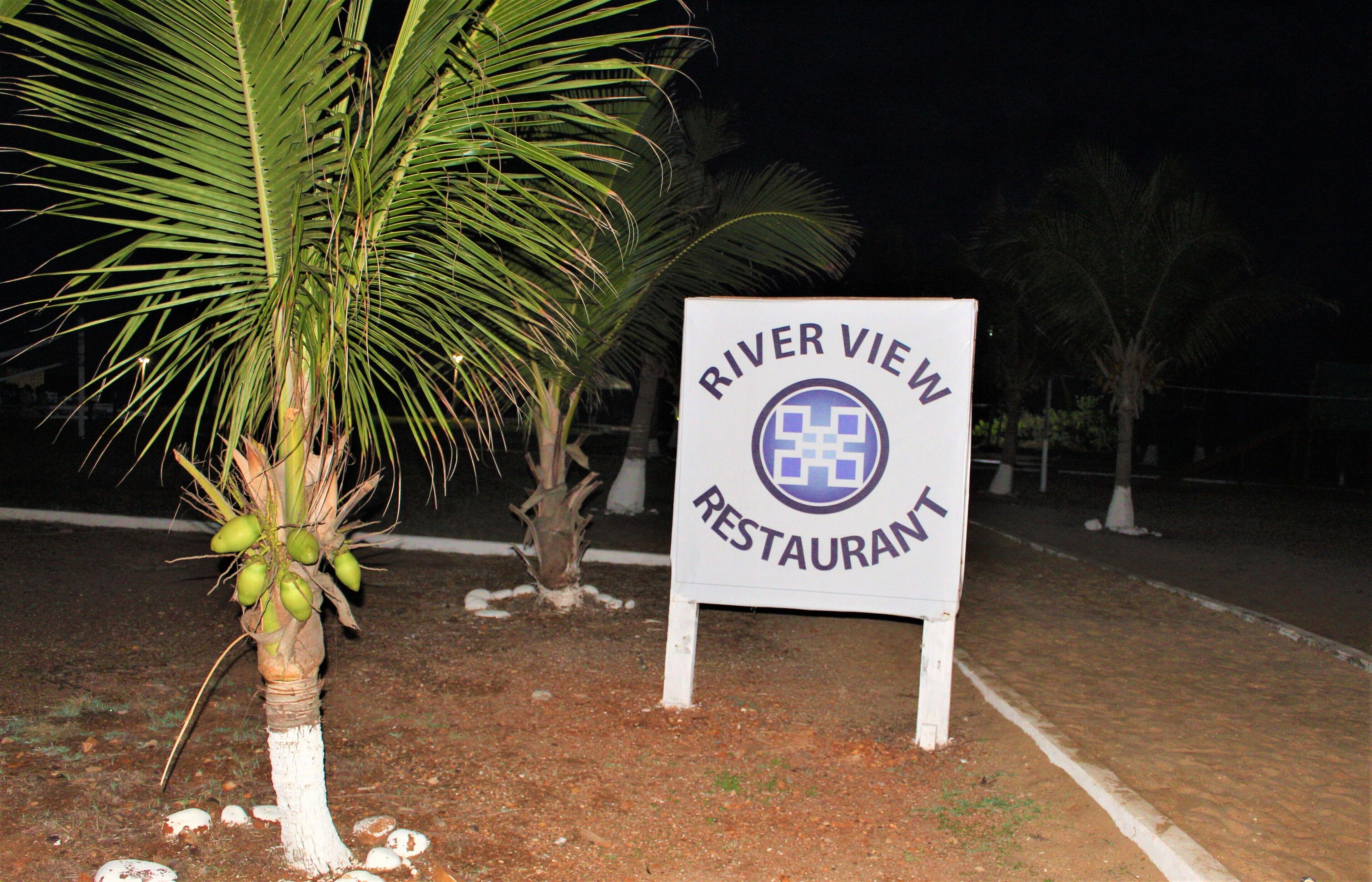 A sign for River View Restaurant with a palm tree in the foreground.