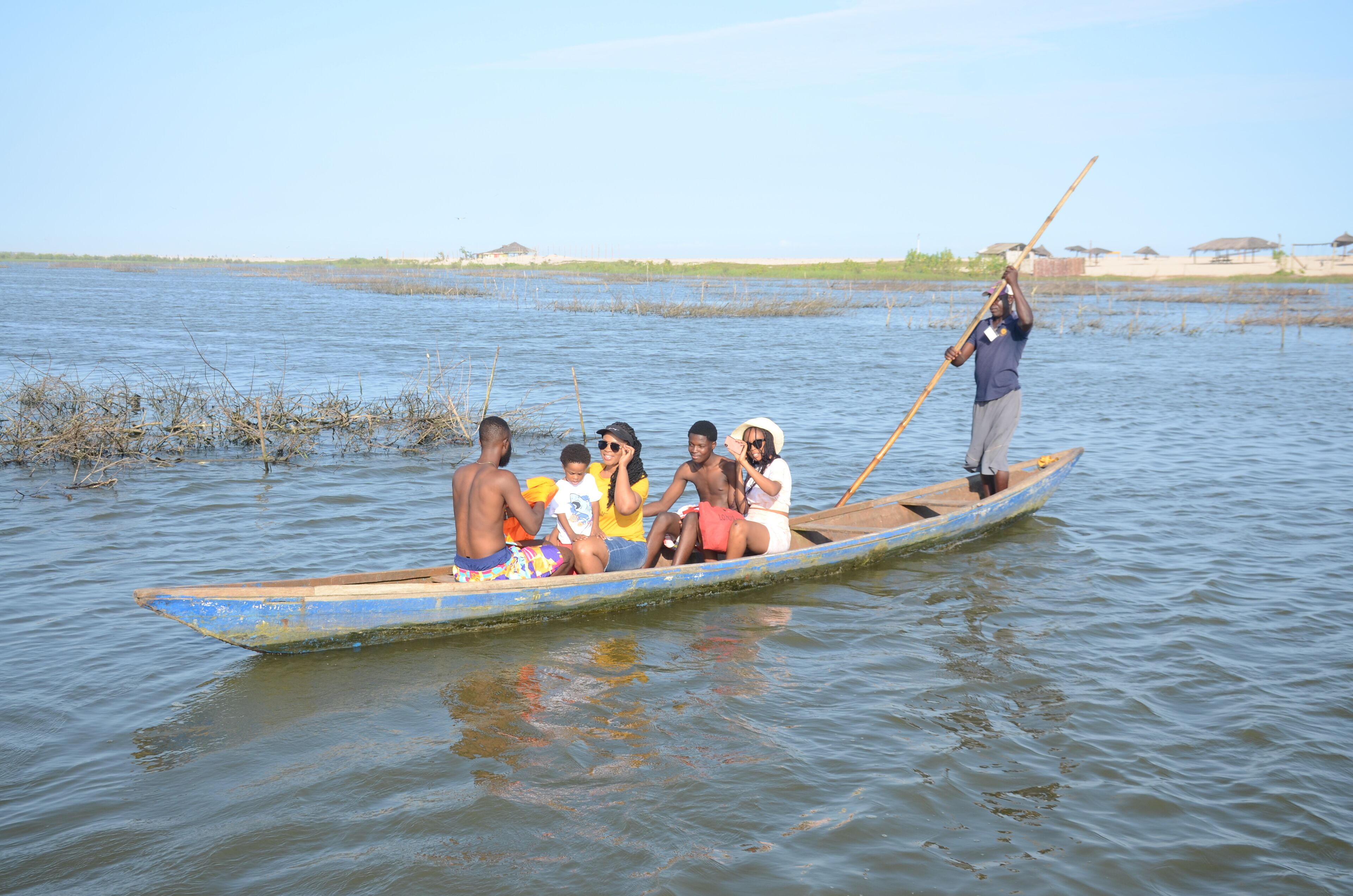 A group of people in a small wooden boat on a calm body of water.