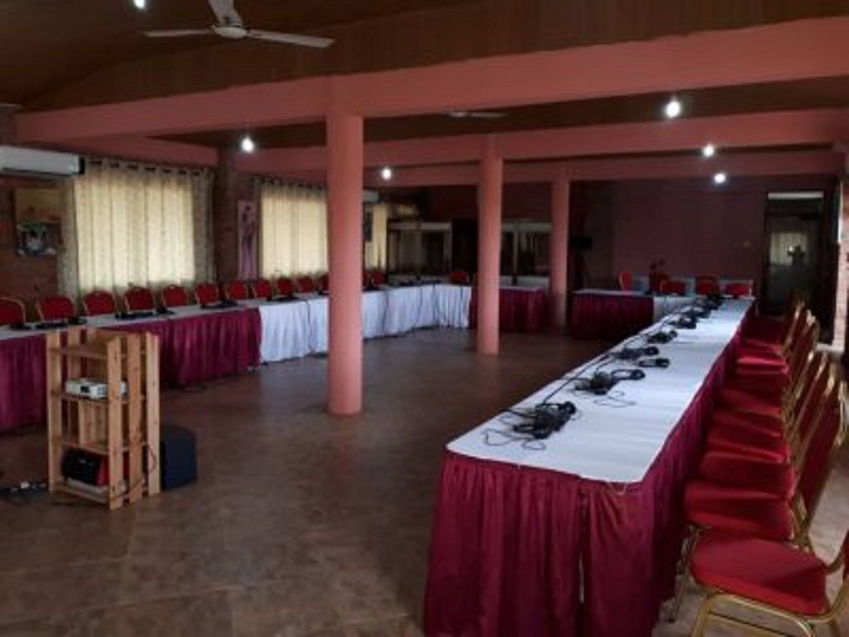 A conference room with a long table, red chairs, and a wooden podium.