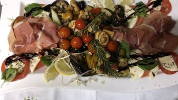 A charcuterie board with various meats, cheeses, and vegetables.