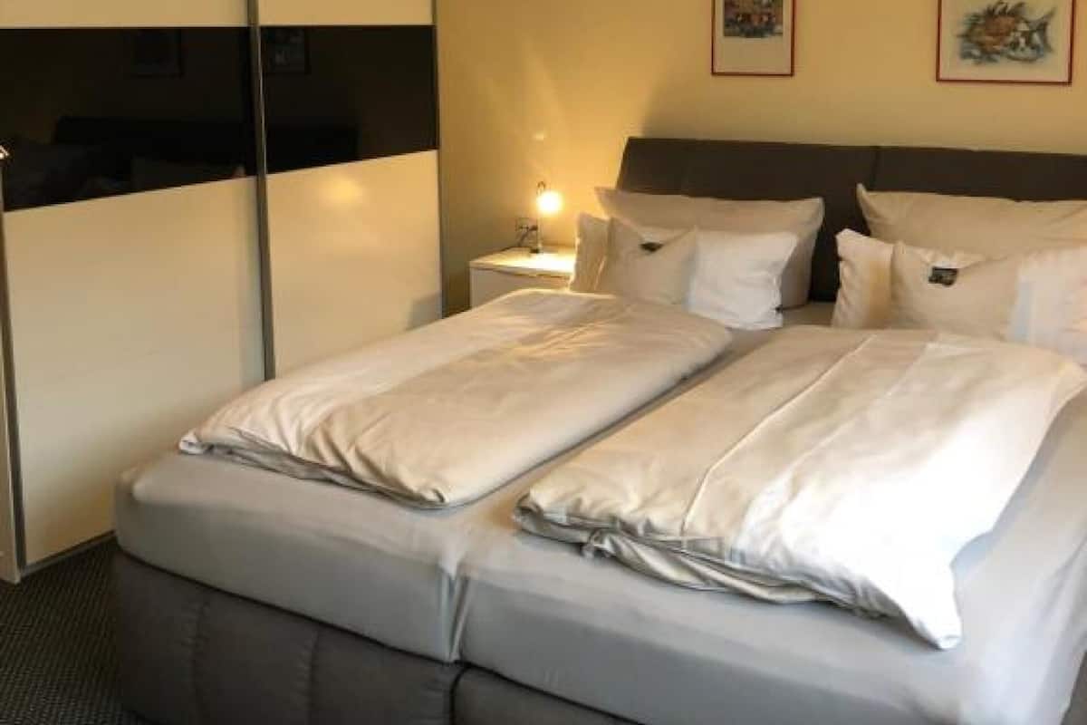 A hotel room with a bed, a wardrobe, and two framed pictures on the wall.