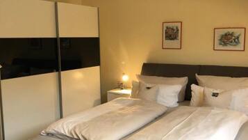 A hotel room with a bed, a wardrobe, and two framed pictures on the wall.
