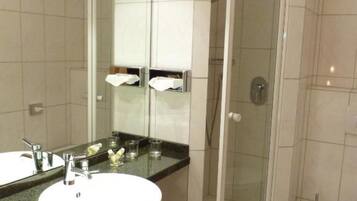 A modern bathroom with a large mirror, two sinks, a shower enclosure, and a toilet.