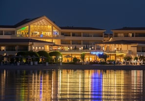 A hotel with multiple balconies, outdoor seating, and a reflection in the water. - Cleopatra Luxury Resort Makadi Bay (Makadi Bay)