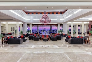 A spacious lobby with multiple seating areas, a large chandelier, and a view of the cityscape through large windows. - Cleopatra Luxury Resort Makadi Bay (Makadi Bay)