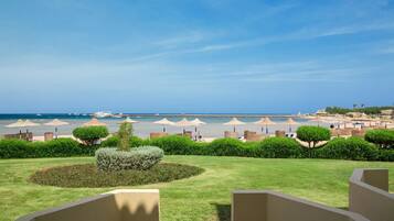 Vista de un resort con piscina, sombrillas y una playa al fondo.