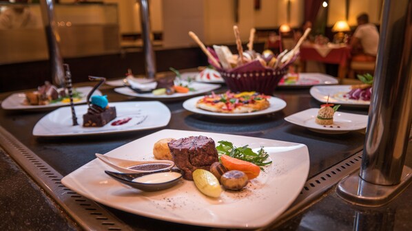 A buffet table with various plated dishes including a steak, vegetables, and desserts.
