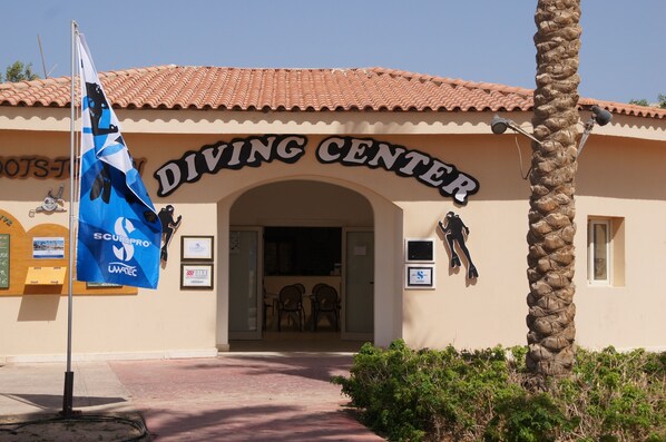 A building with a sign reading "DIVING CENTER" and a flag with "SCUBAPRO" and "LWA TEC" logos. - Cleopatra Luxury Resort Makadi Bay (Makadi Bay)