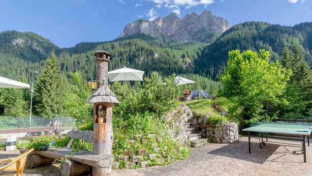 A mountain view with a wooden structure, outdoor seating, and a ping pong table. - Pineta Pastry Hotel (Rocca Pietore)