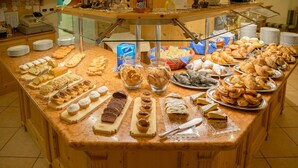 A buffet counter with various pastries and desserts displayed on a marble countertop. - Pineta Pastry Hotel (Rocca Pietore)