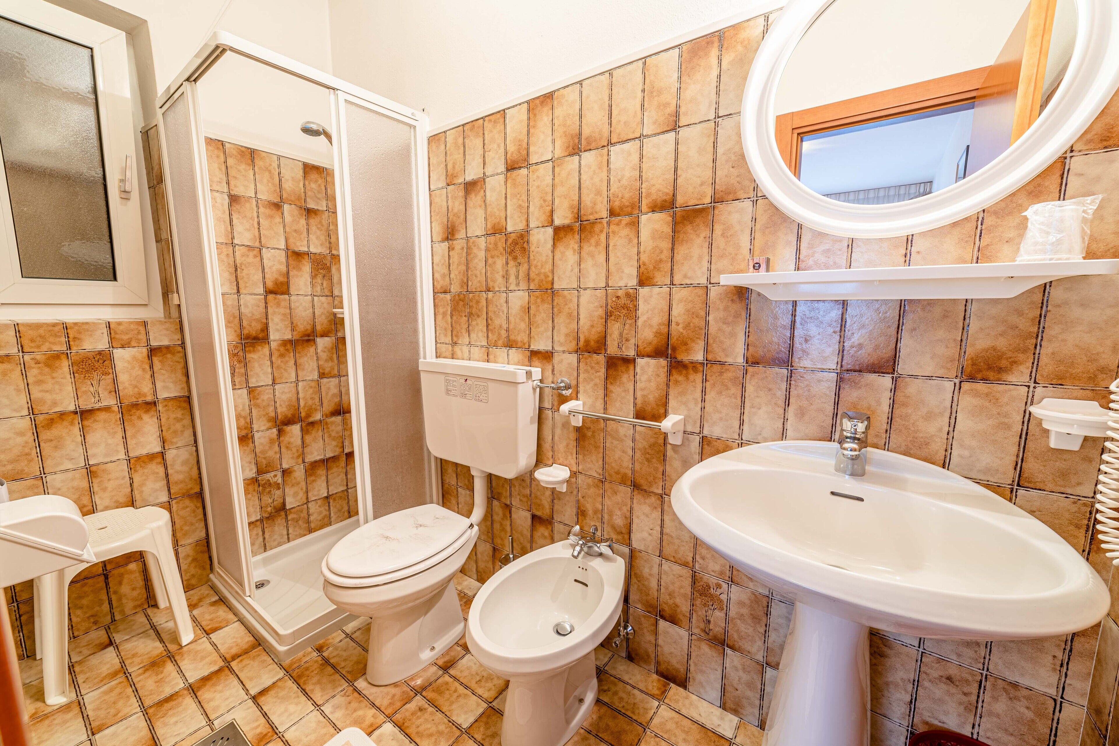 Un bagno completo con doccia, WC, bidet e lavandino.